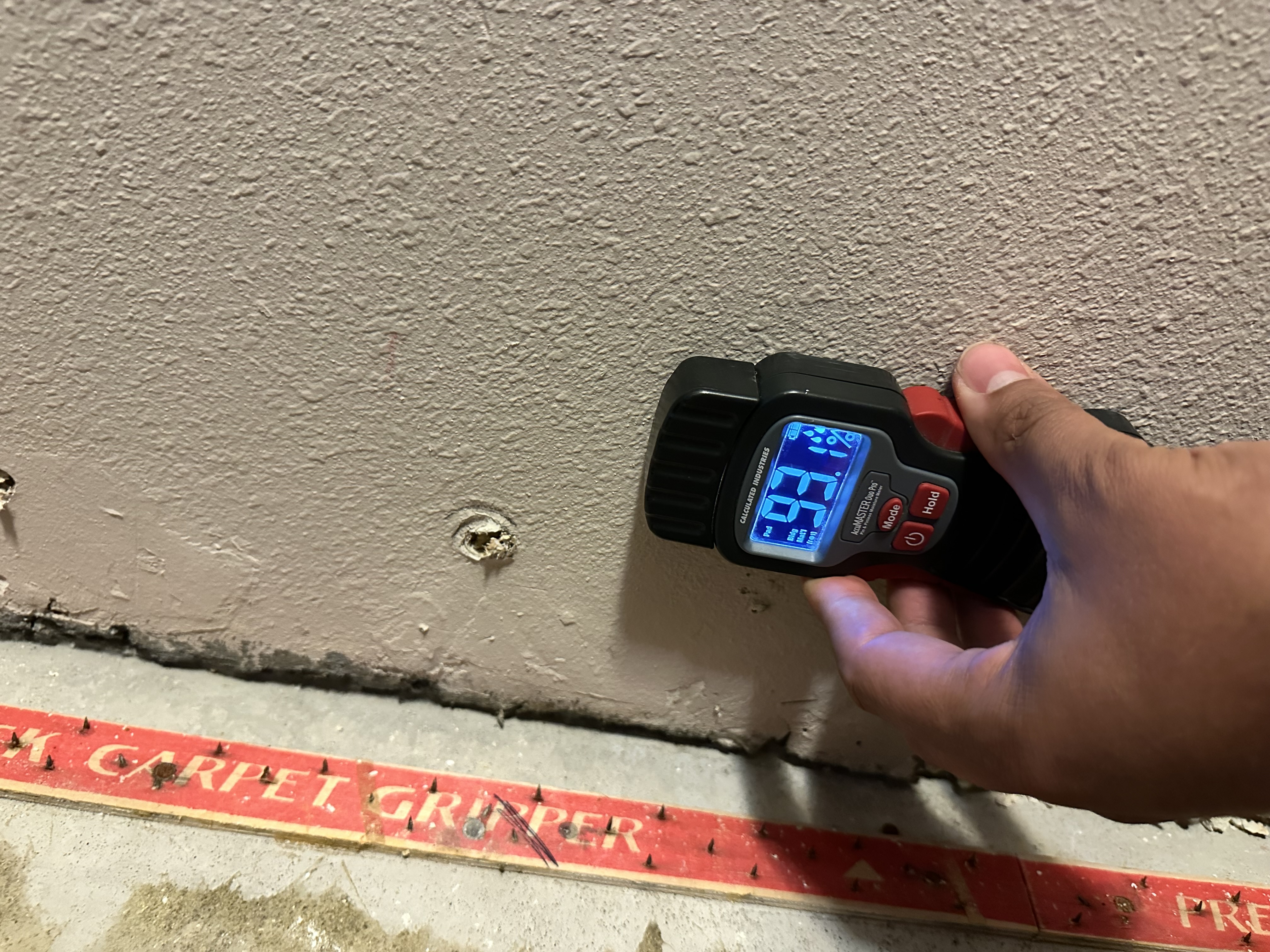 Professional moisture meter detecting water damage in wall - Fire Water Wind restoration